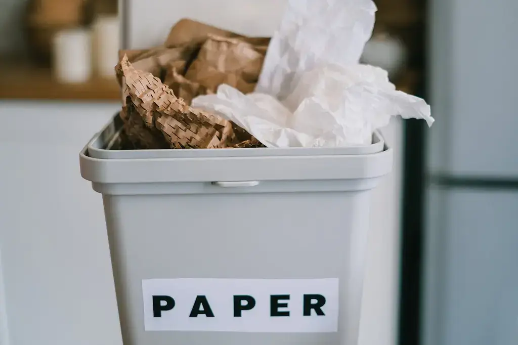 A plastic bin with paper rubbish in